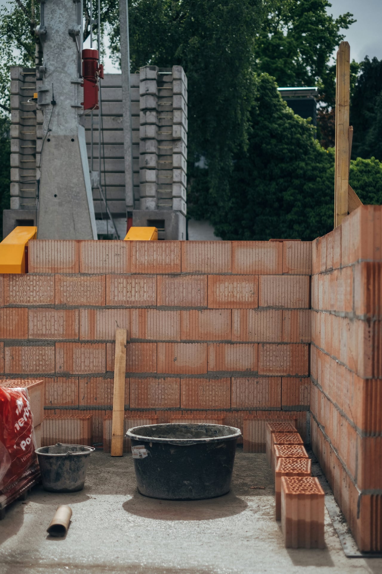 Muro de ladrillos en obra con baldes y materiales de albañilería